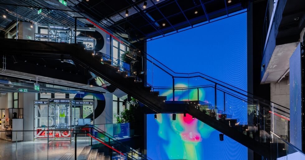 Nike House of Innovation Parigi: scala a spirale sospesa con sfondo di schermo LED a parete, architettura retail futuristica
